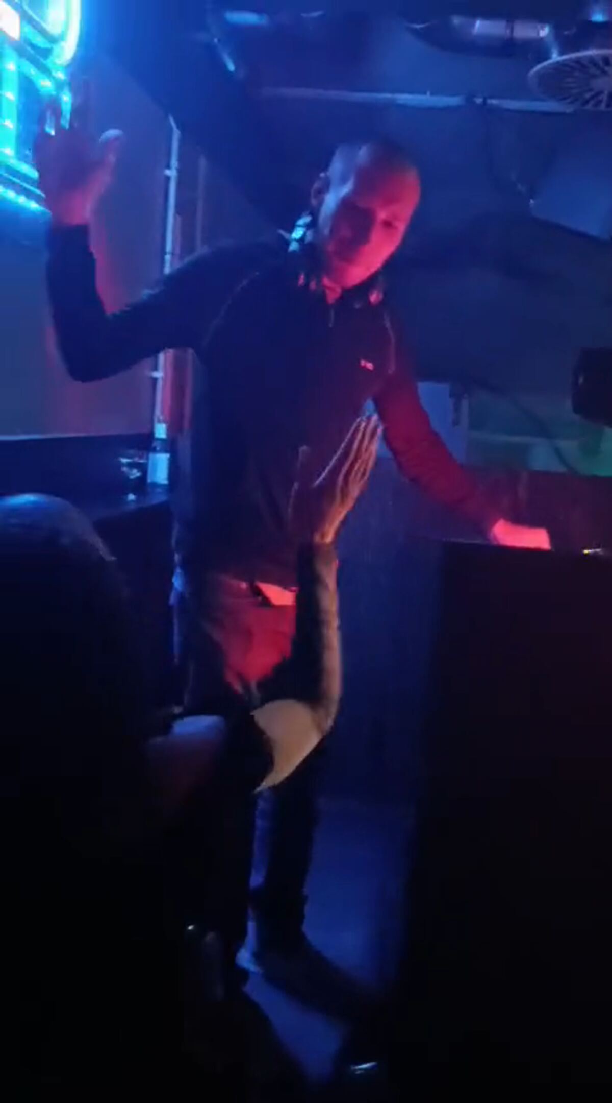 Dark club room in blue light, a person dancing in front of the stage