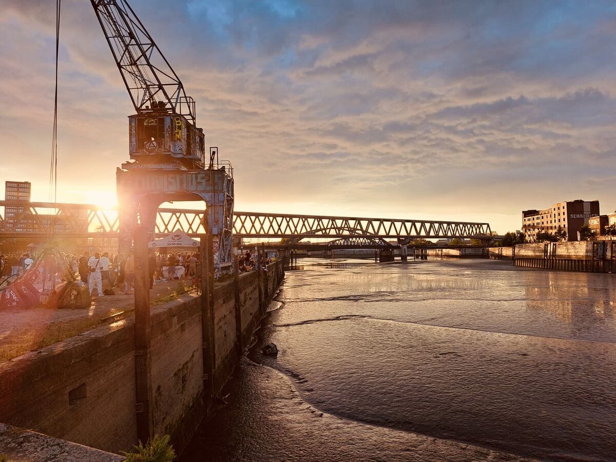 Old harbour crane at sunset above Billhafen, people along the quay