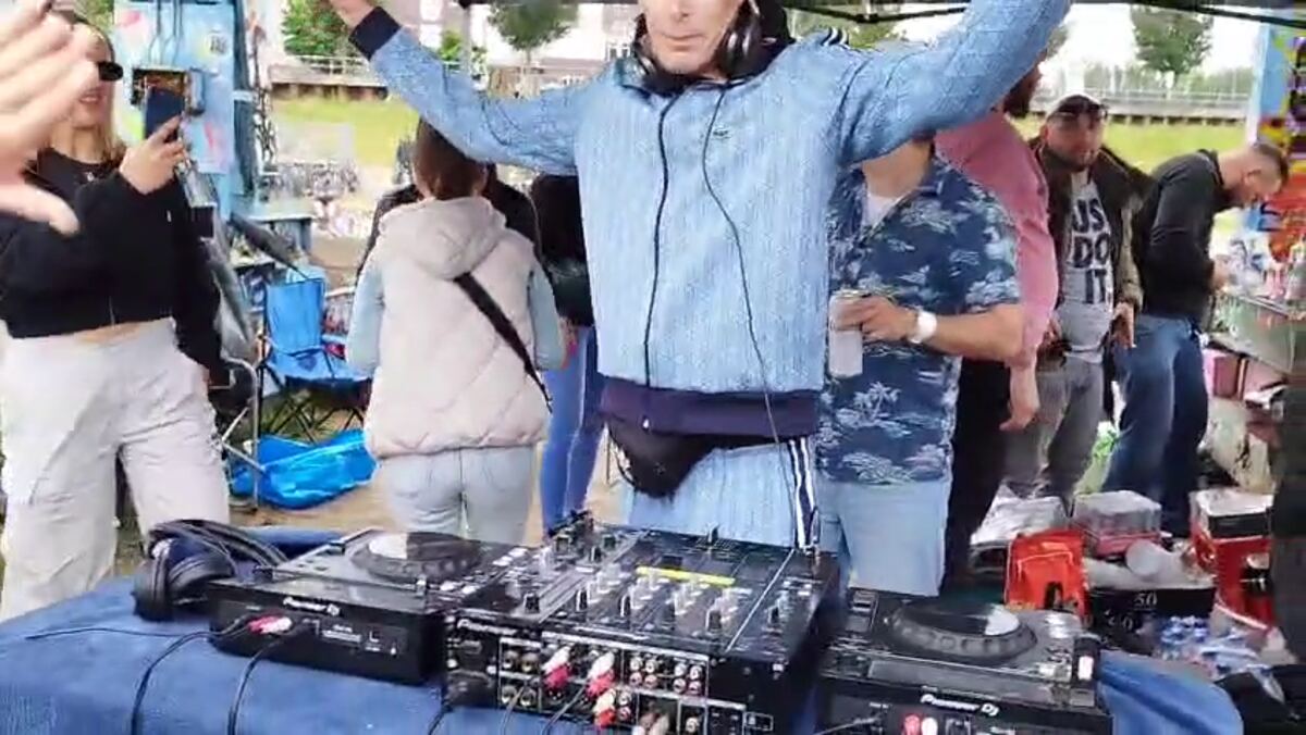 Stefan Brandenburg with raised arms behind the mixer, a dancing crowd in front