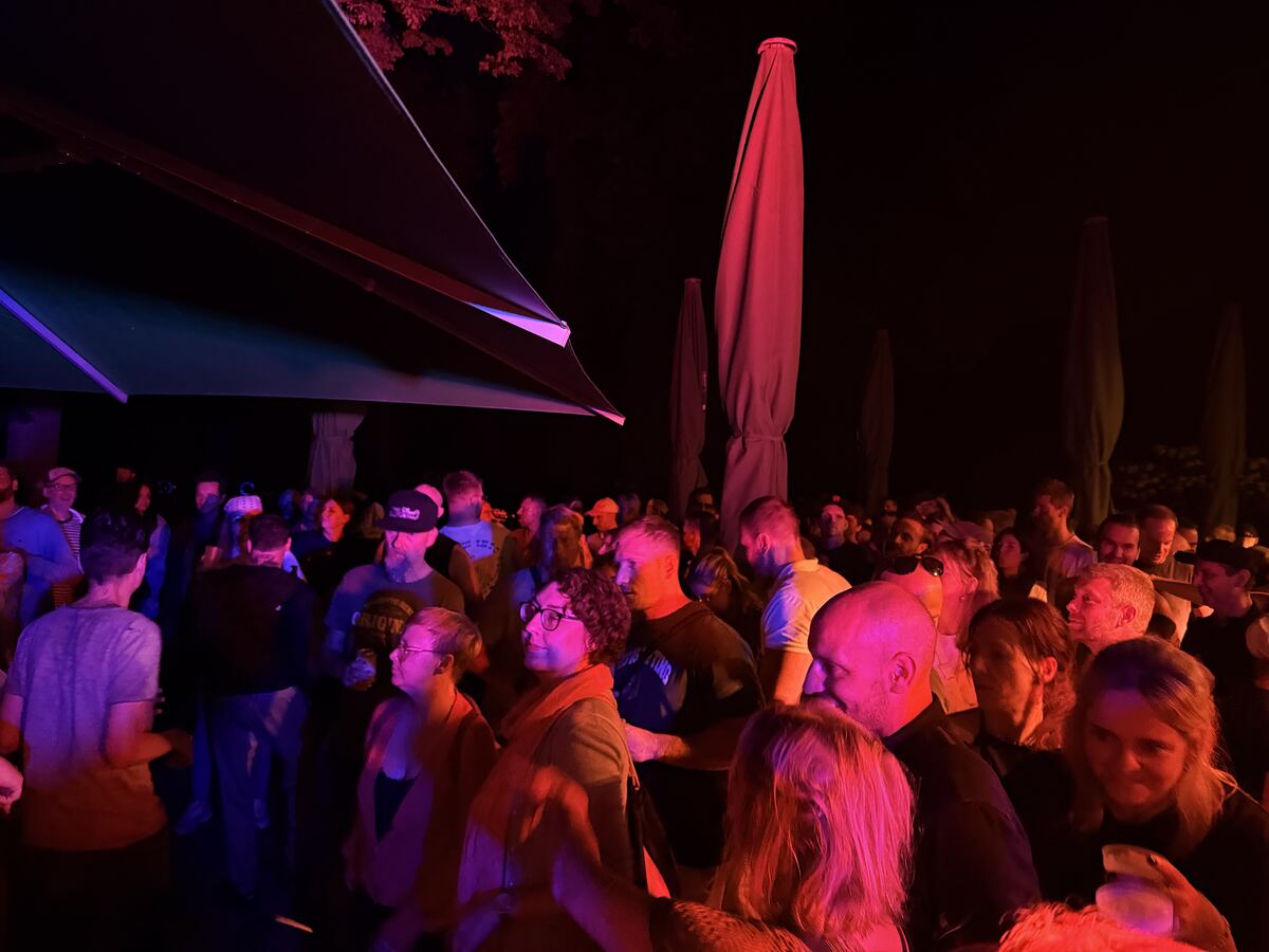 Crowd at night under parasols, a green laser beam above their heads