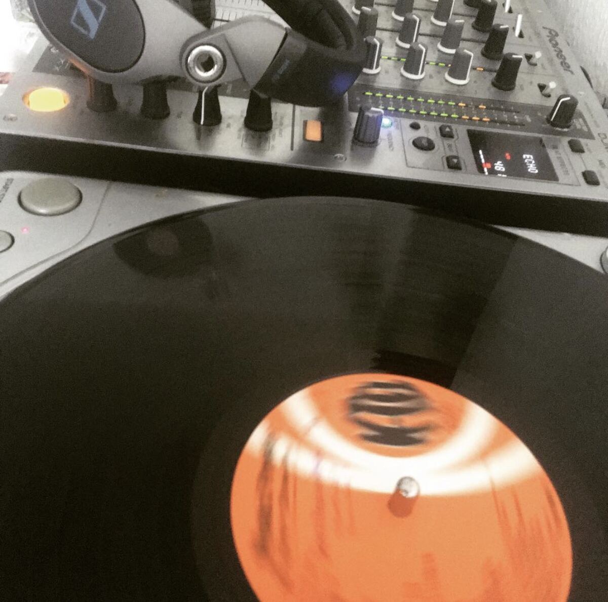 A record spinning on the turntable, next to it a Pioneer mixer and headphones