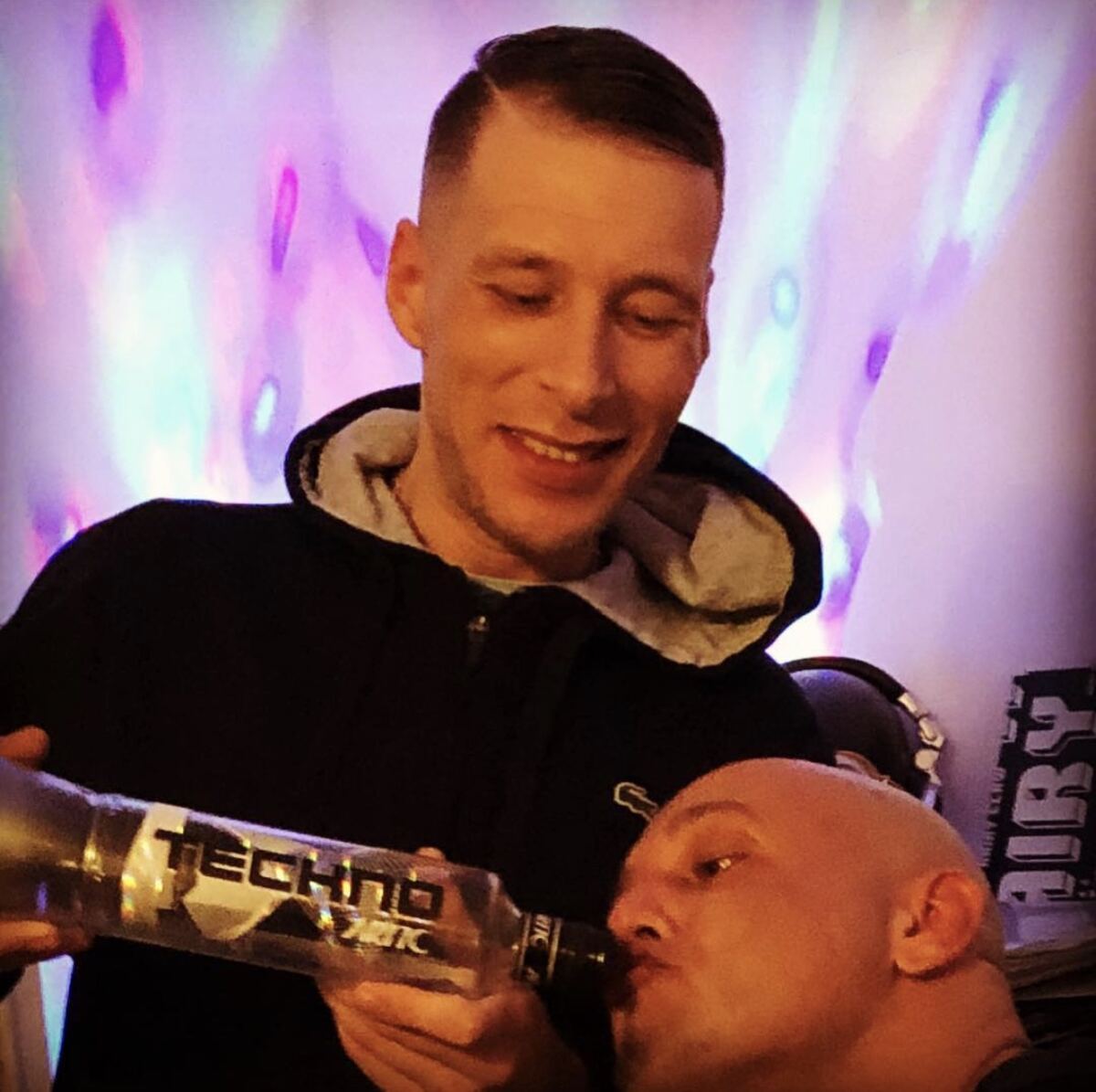 Two friends toasting after the show, disco lights behind